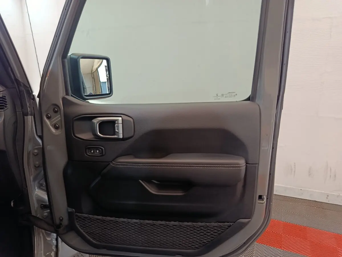 Vue intérieure de la porte avant gauche gris foncé du Jeep Wrangler 2022 avec poignée et filet de rangement.