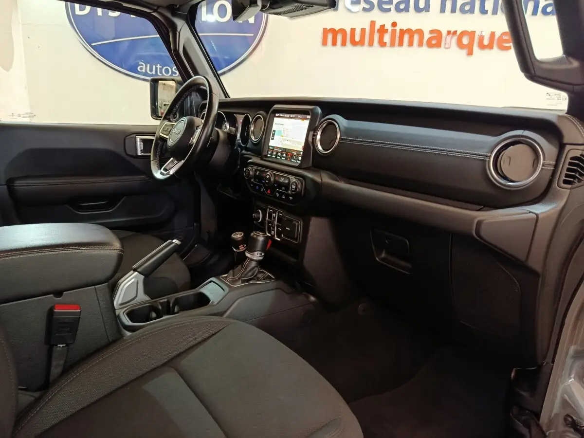Vue intérieure côté conducteur du Jeep Wrangler 2022, tableau de bord noir avec écran tactile central et volant cuir multifonctions.