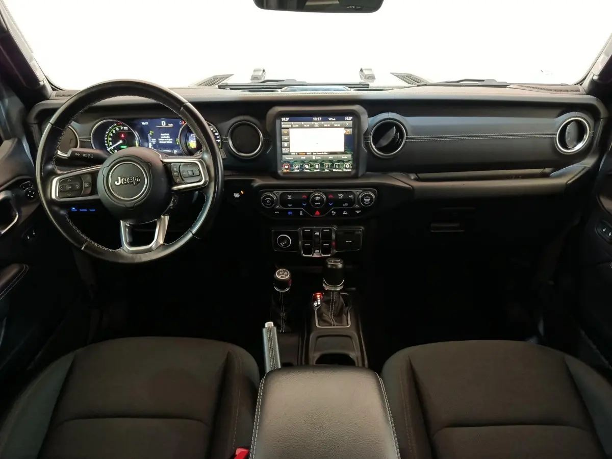 Vue intérieure frontale du tableau de bord noir du Jeep Wrangler 2022 avec écran tactile central et volant cuir multifonctions.