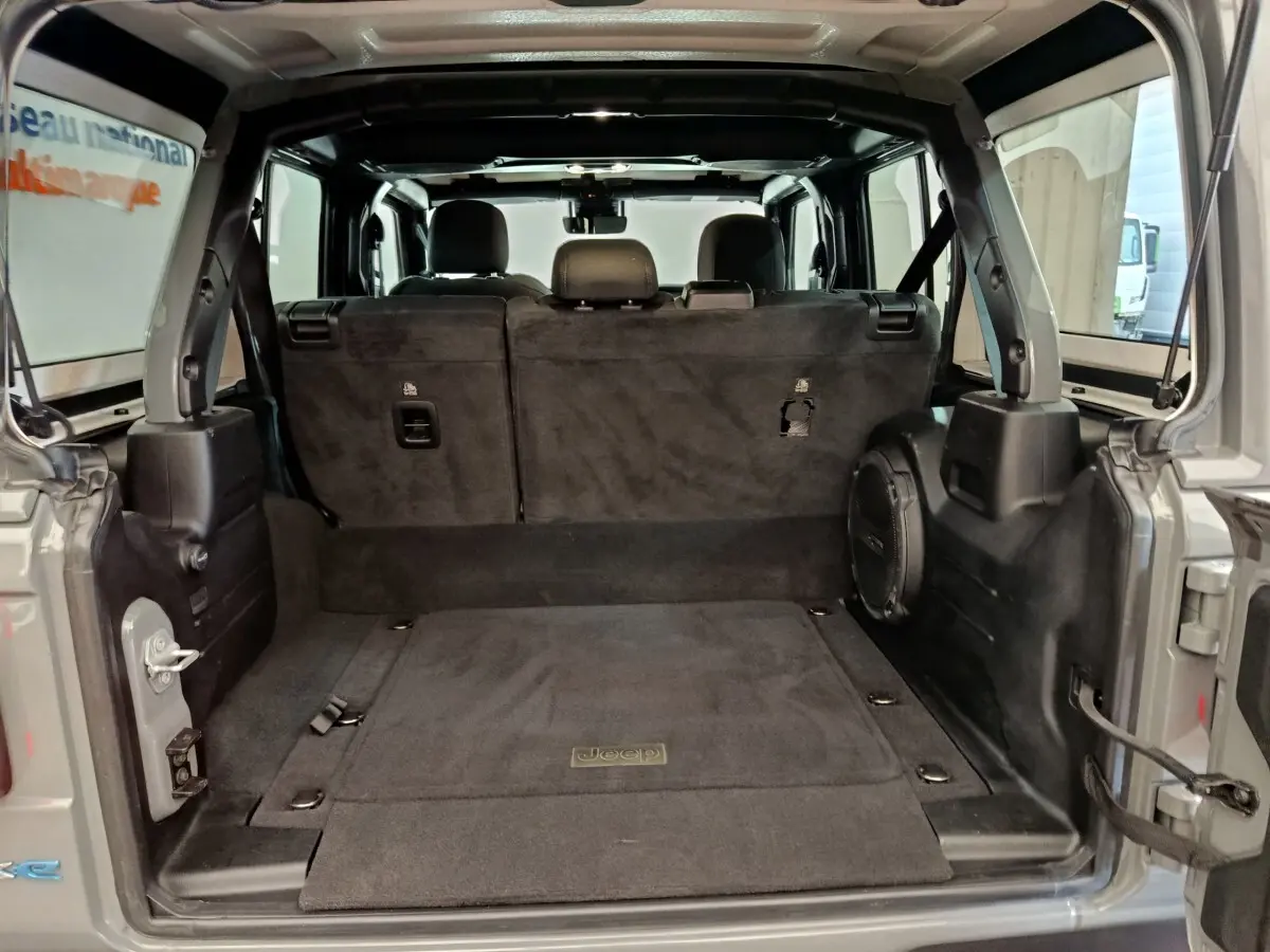 Vue arrière du coffre ouvert d’un Jeep Wrangler gris foncé 2022, montrant l’intérieur spacieux avec banquette arrière rabattue.
