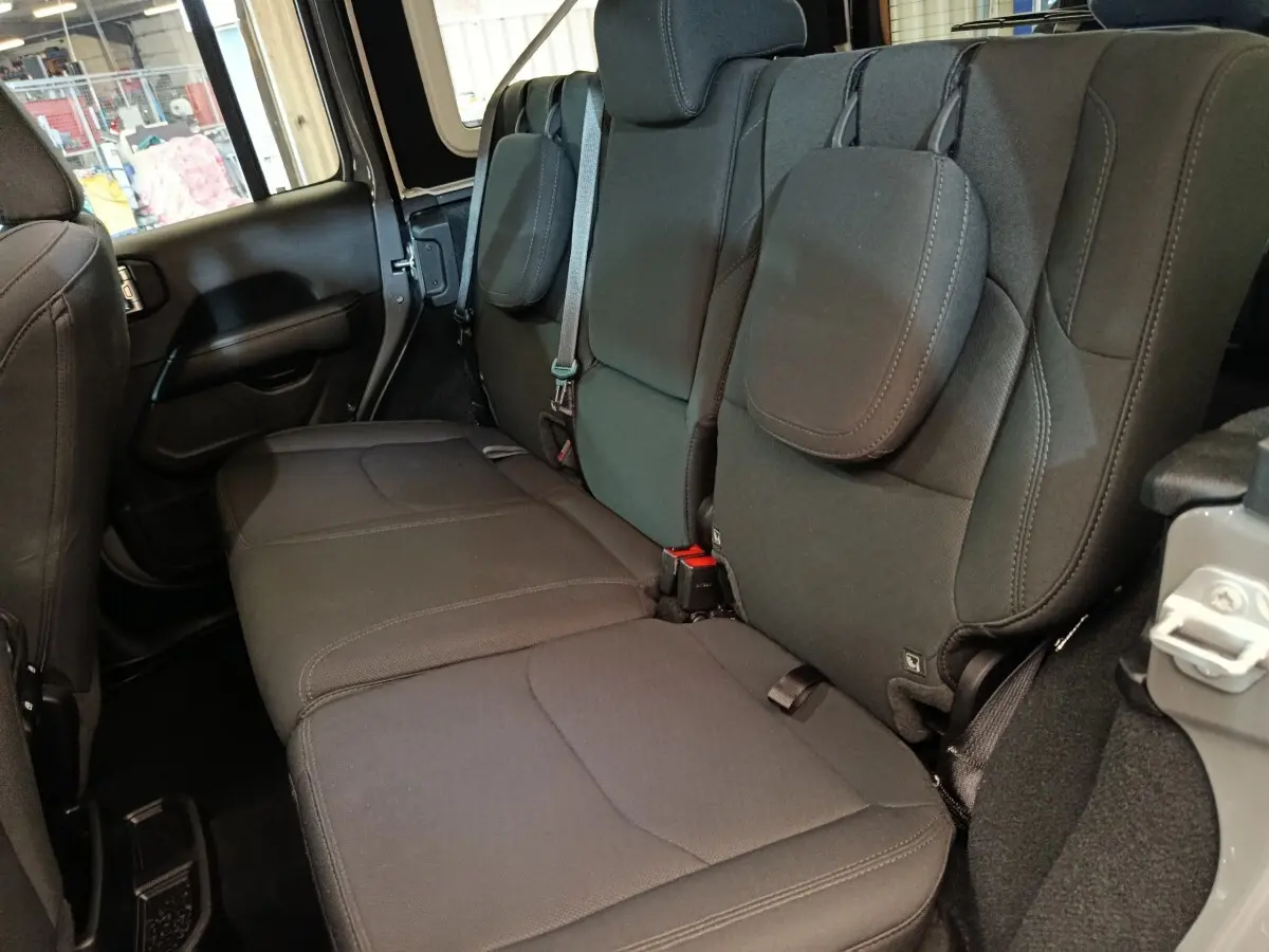 Vue latérale droite sur la banquette arrière noire du Jeep Wrangler Sahara 2022, avec appuie-têtes et ceintures visibles.
