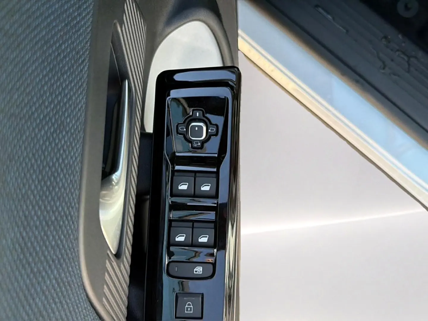 Gros plan sur la commande des vitres électriques côté conducteur du Citroën C5 Aircross blanc et noir, porte ouverte.