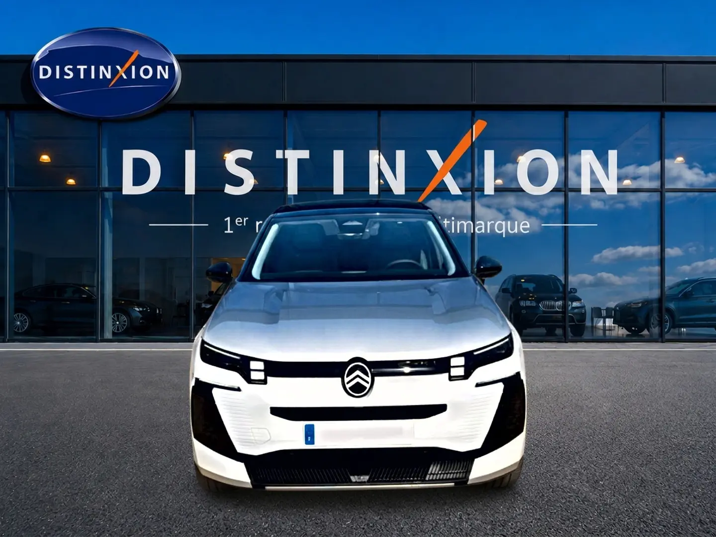 Vue de face du Citroën C5 Aircross blanc et noir avec calandre moderne et logo centré devant un bâtiment vitré.
