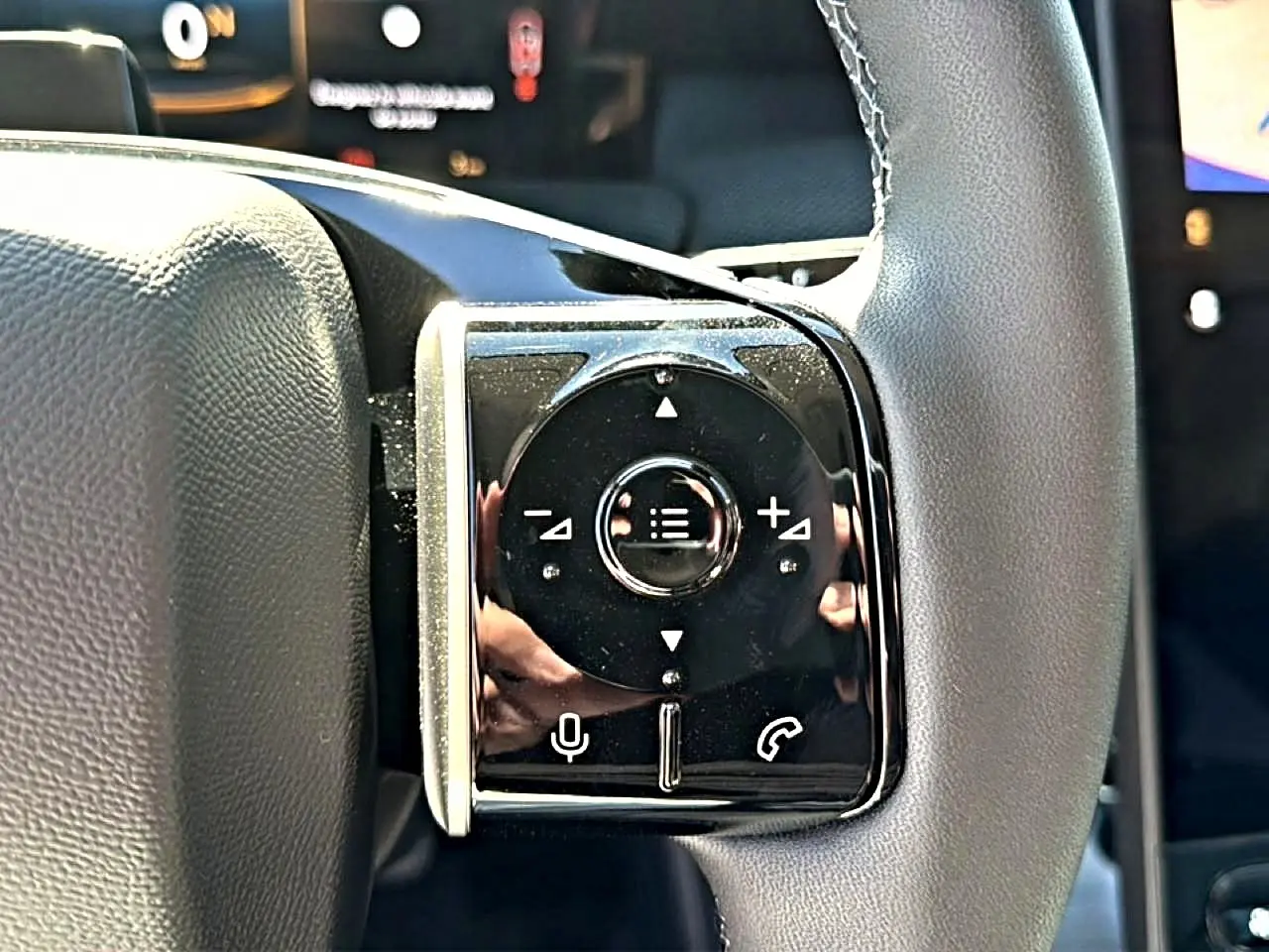 Gros plan sur les commandes multifonctions noires à gauche du volant gris du Citroën C5 Aircross hybride 2026.
