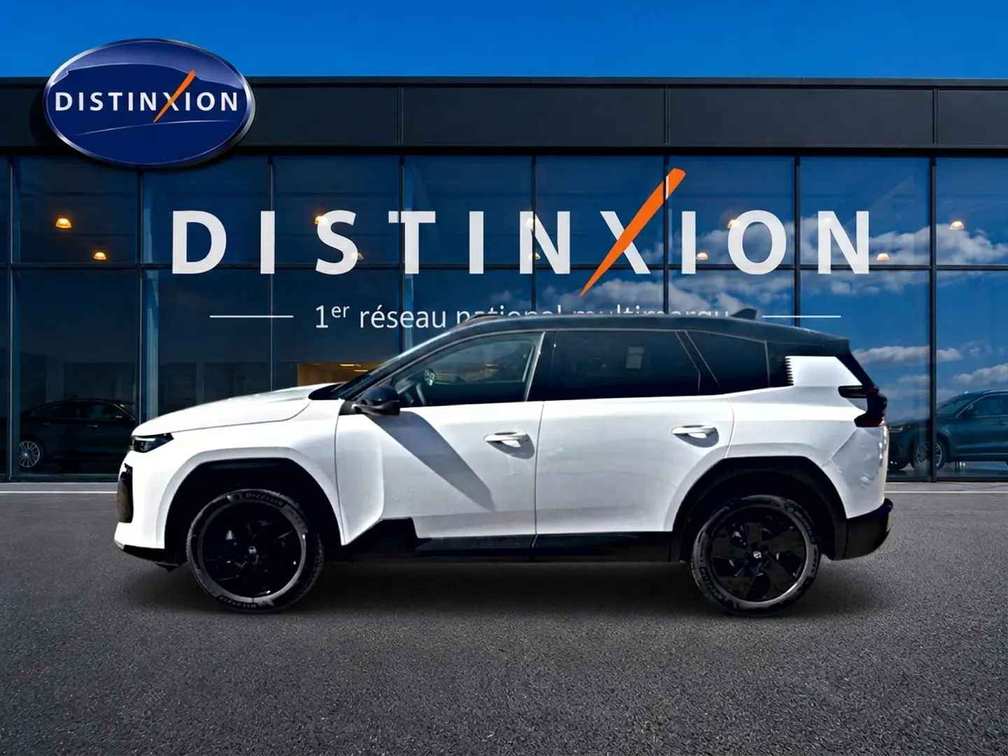 Profil côté gauche du Citroën C5 Aircross blanc et noir avec jantes alliage noires devant une vitrine Distinxion.