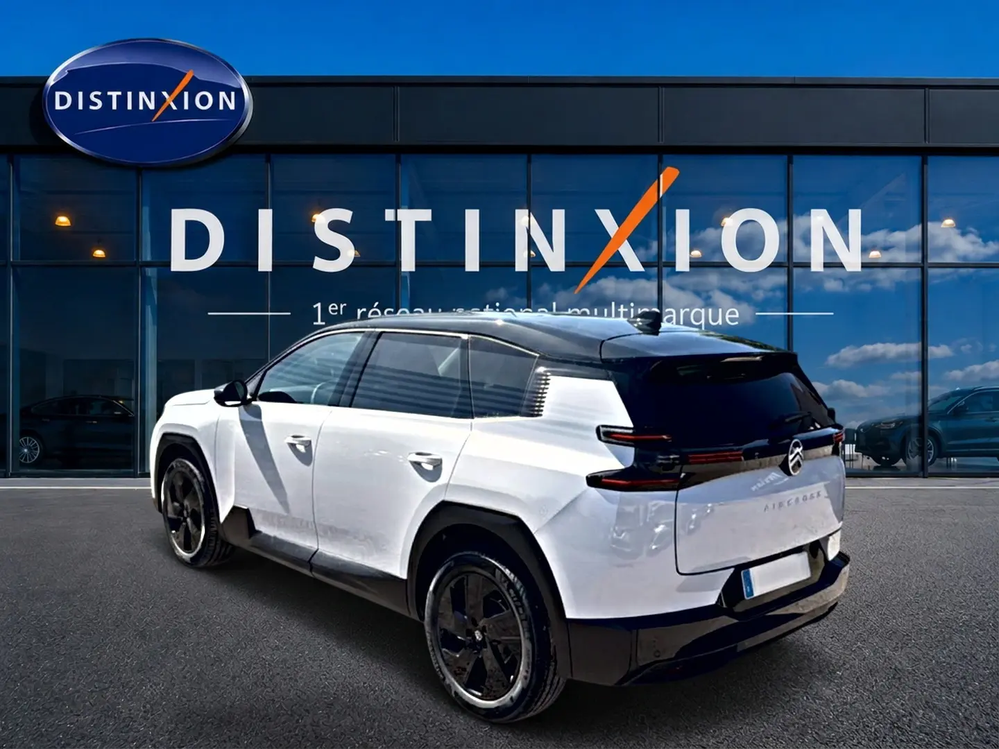 Vue 3/4 arrière droite du Citroën C5 Aircross blanc et noir avec jantes alliage 19 pouces devant un showroom Distinxion.