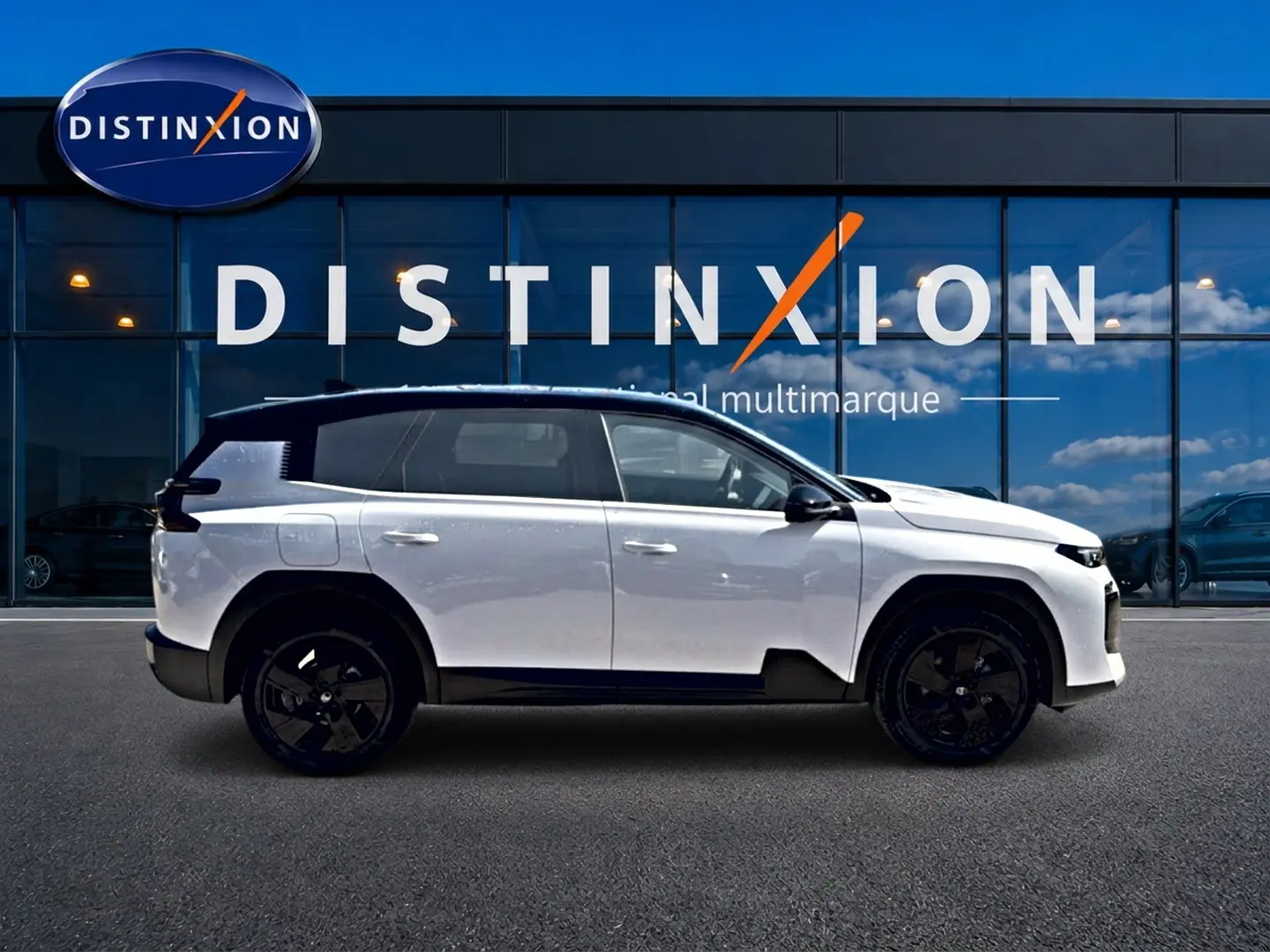 Profil droit du Citroën C5 Aircross hybride blanc avec toit noir, jantes alliage noires, devant une vitrine Distinxion.