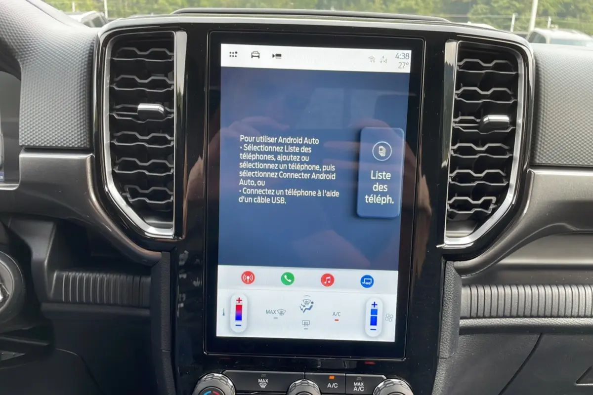 Écran tactile central du Ford Ranger 2025 gris carbone, vue rapprochée du tableau de bord avec commandes climatisation visibles.