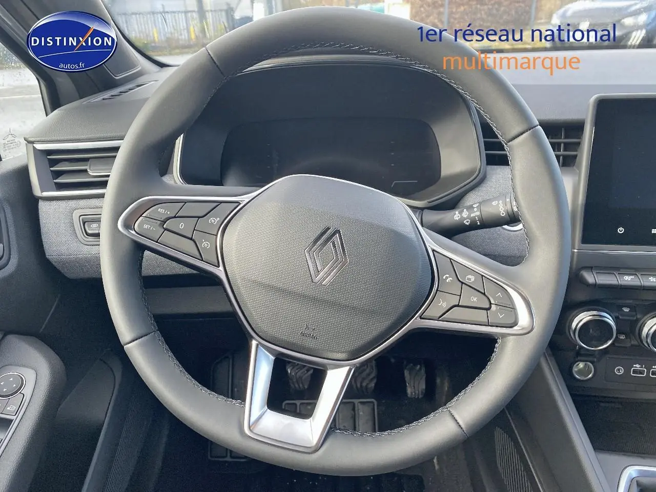 Vue rapprochée du volant multifonction noir de la Renault Clio V 1.0 TCe 90 Techno avec tableau de bord et écran tactile.