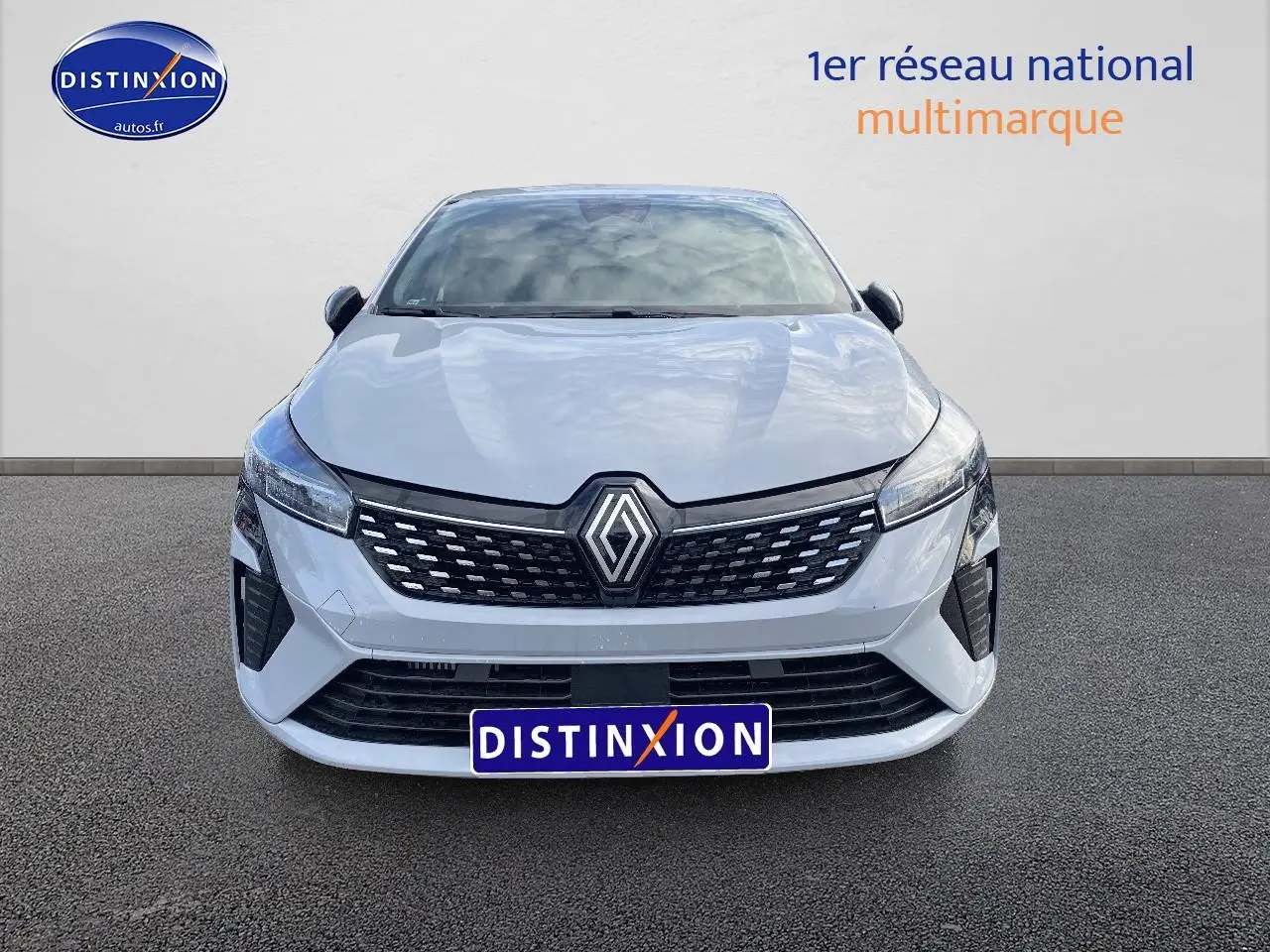 Vue frontale d'une Renault Clio V gris rafale avec calandre noire et logo Renault proéminent.