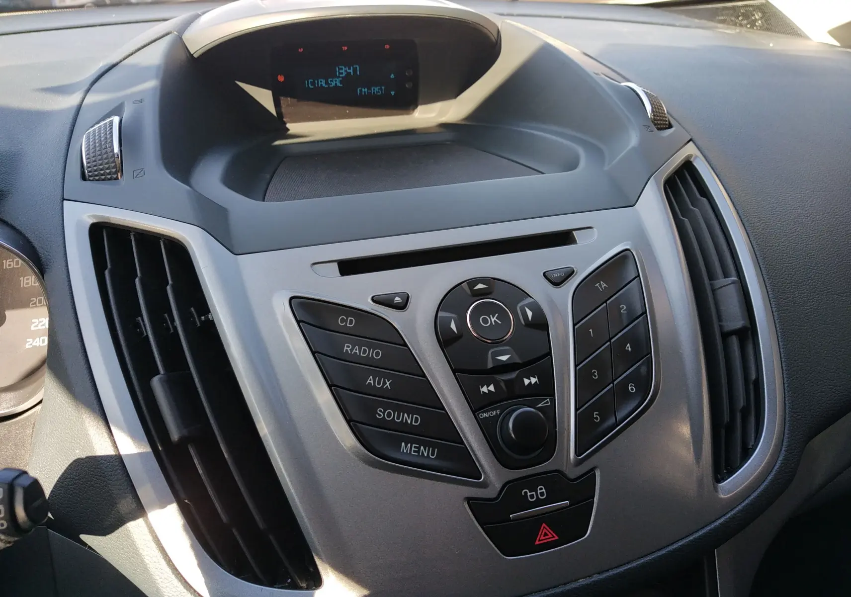 Vue rapprochée du tableau de bord gris et noir de la Ford C-MAX 1.0 Ecoboost 2013 avec commandes audio et écran central.