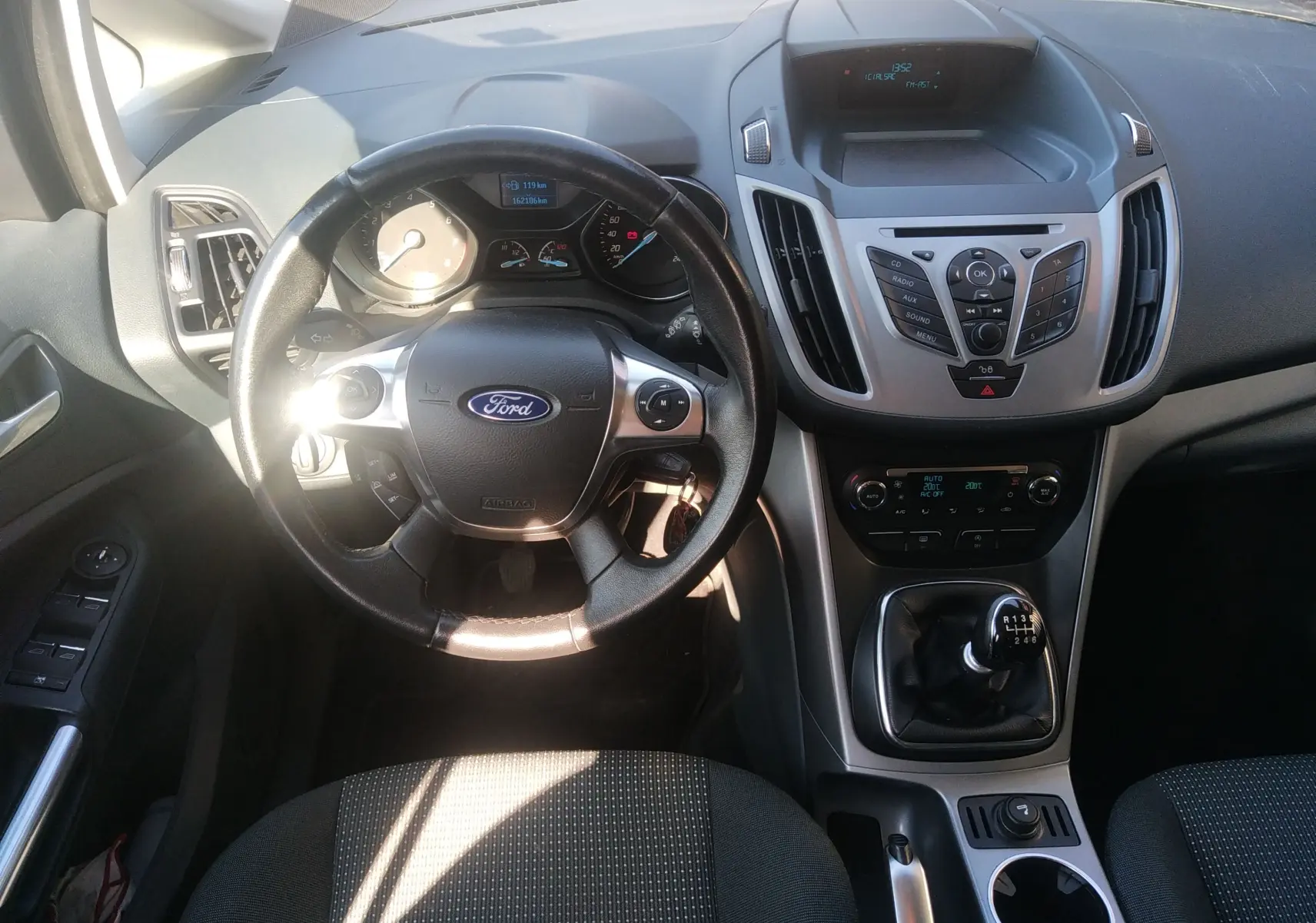 Vue intérieure centrée sur le volant et la console centrale d'une Ford C-MAX 2013 avec levier de vitesses manuel.