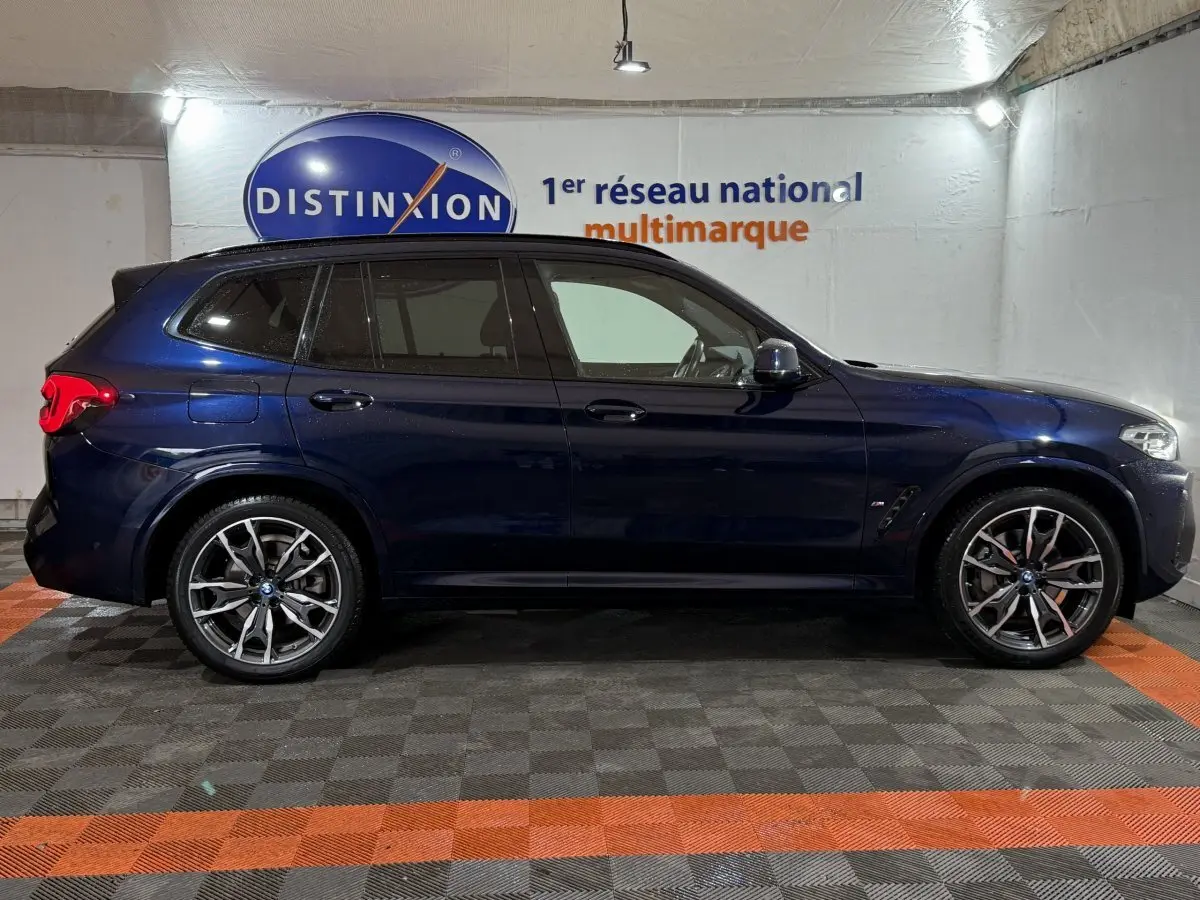 BMW X3 xDrive30e bleu en vue profil côté gauche, avec jantes M Sport et vitres teintées.