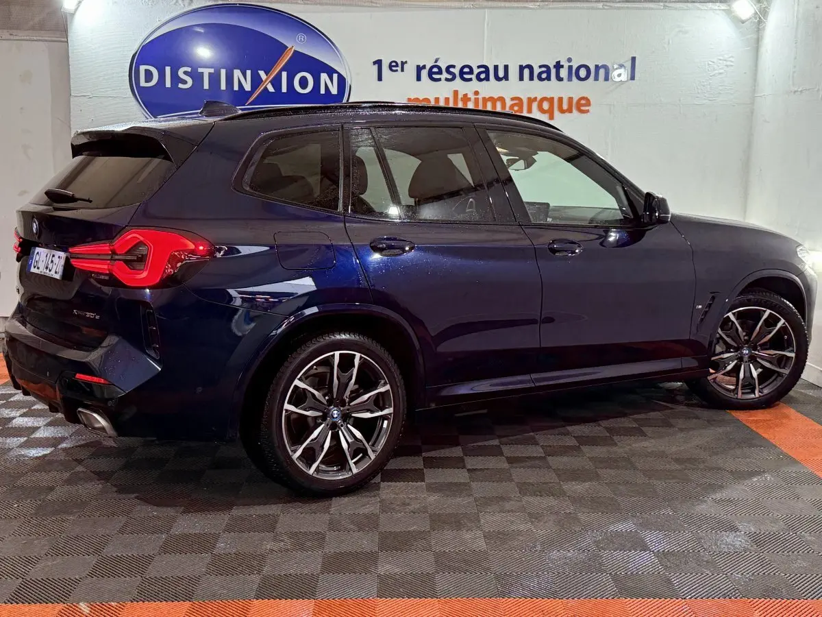 BMW X3 xDrive30e bleu en vue profil droit, avec jantes alliage et feux arrière LED distinctifs.