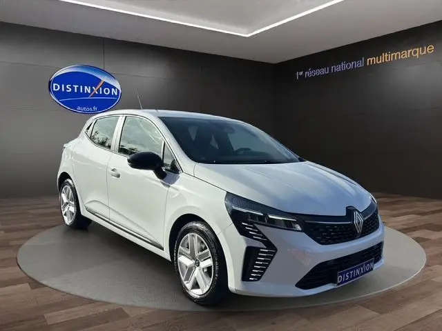 Renault Clio V blanc vue 3/4 avant gauche, avec phares LED et jantes alliage 16 pouces en showroom.