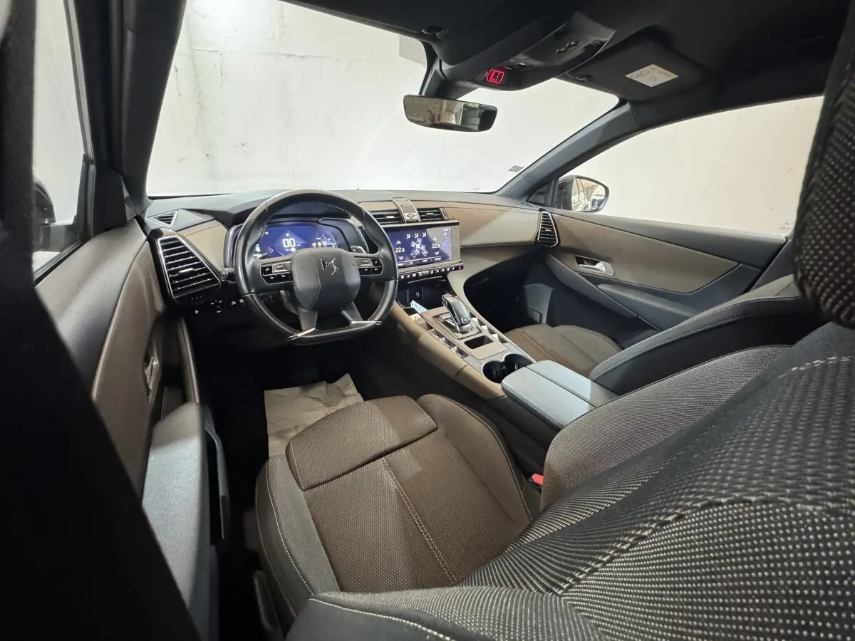 Intérieur du DS7 Crossback vu côté conducteur, tableau de bord moderne avec écran tactile et volant multifonctions noir.
