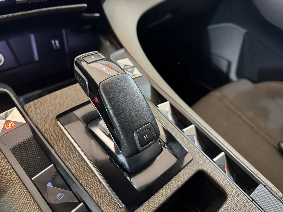 Gros plan sur la commande de boîte automatique noire du DS7 Crossback gris foncé, avec détails de la console centrale.