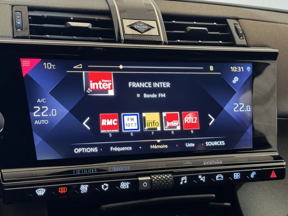 Écran tactile central du tableau de bord du DS7 Crossback 2020 affichant les stations radio, avec commandes climatisation en dessous.