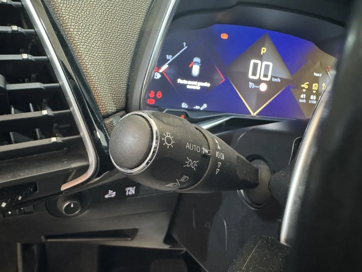 Gros plan sur la commande des phares et le tableau de bord numérique du DS7 Crossback gris foncé, affichage 12 pouces.