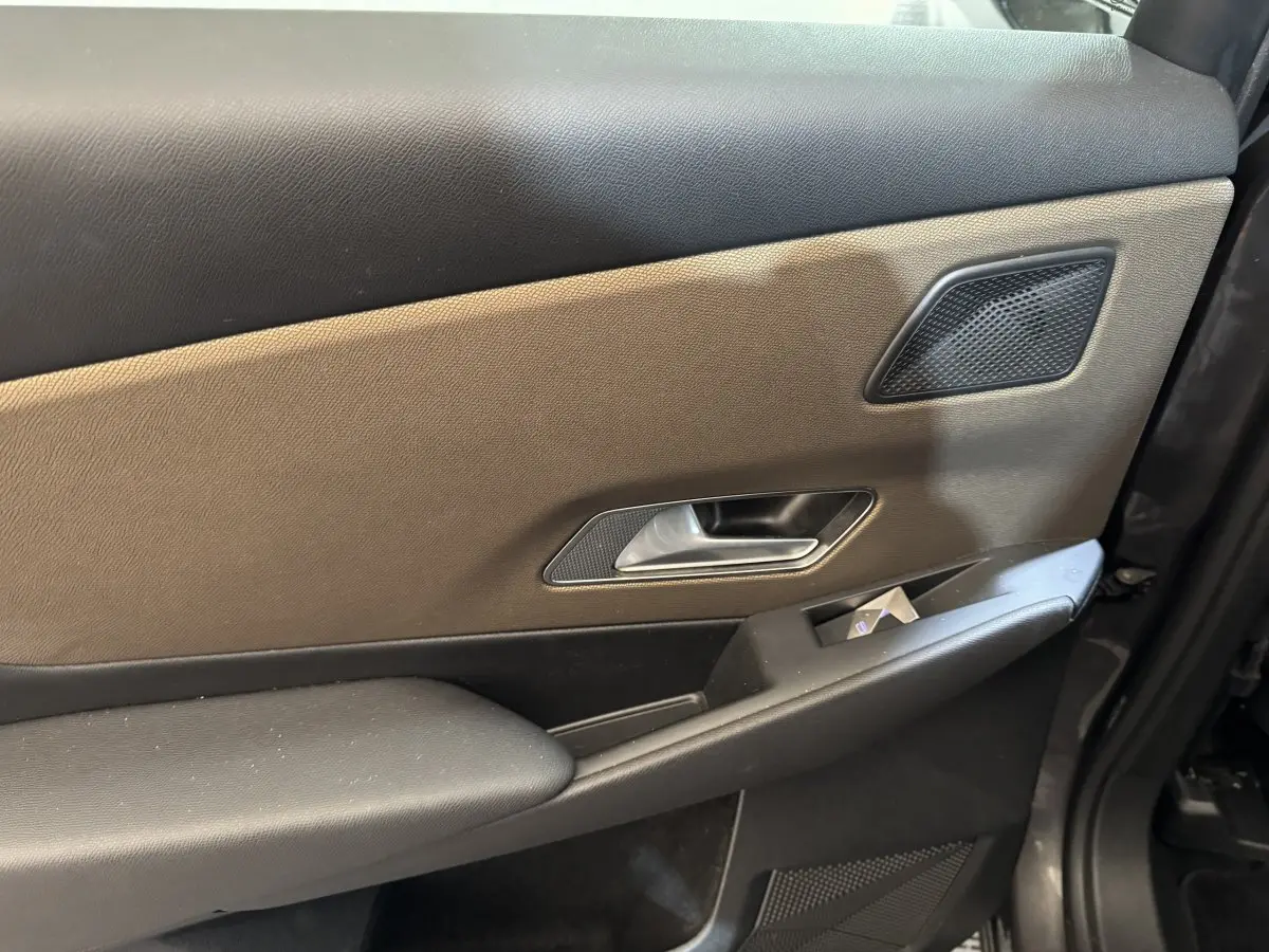 Détail de la porte intérieure côté gauche du DS7 Crossback gris foncé, avec poignée argentée et haut-parleur intégré.