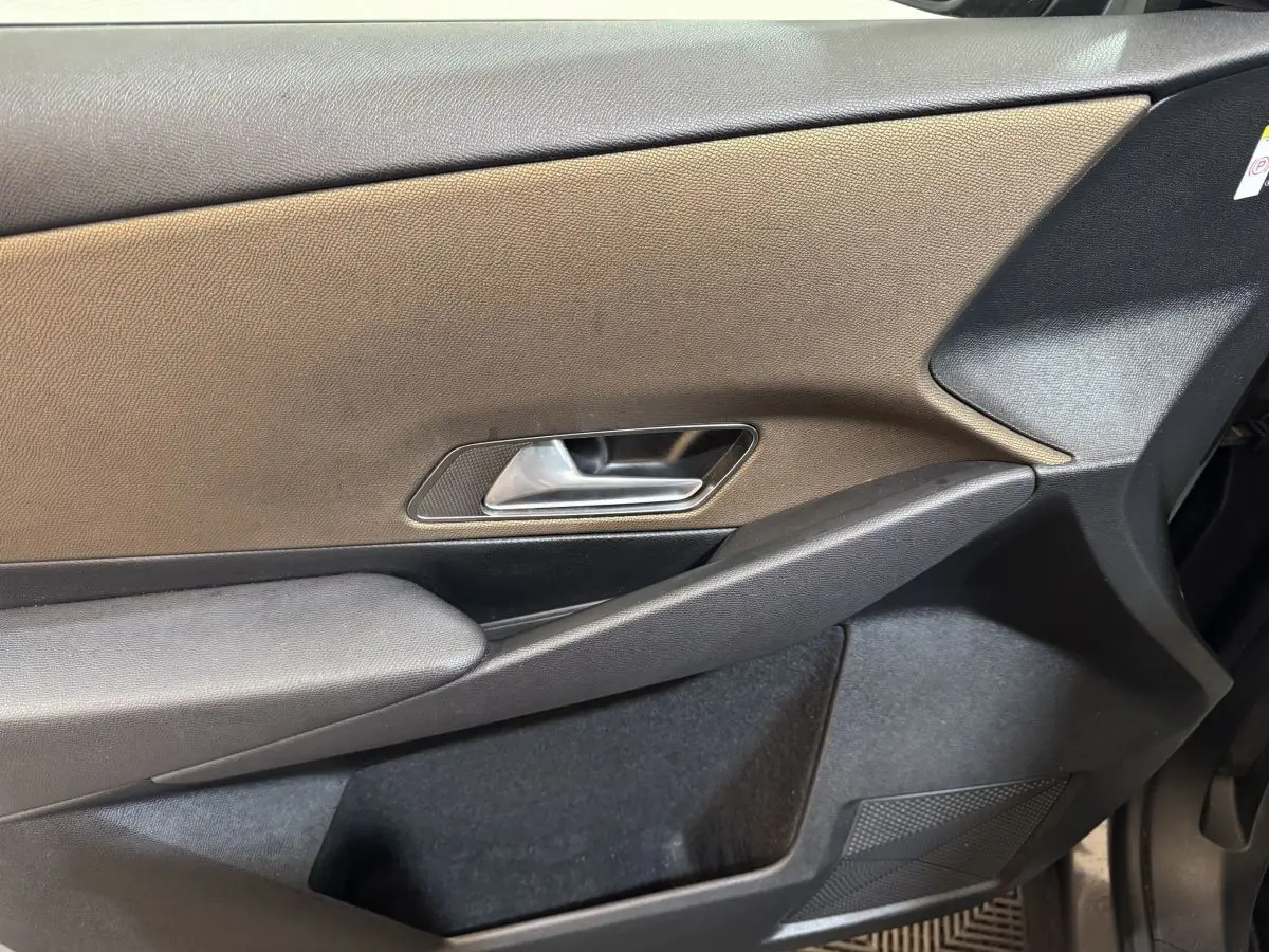 Vue rapprochée de la porte avant gauche du DS7 Crossback gris foncé, montrant la poignée intérieure et le panneau en tissu.