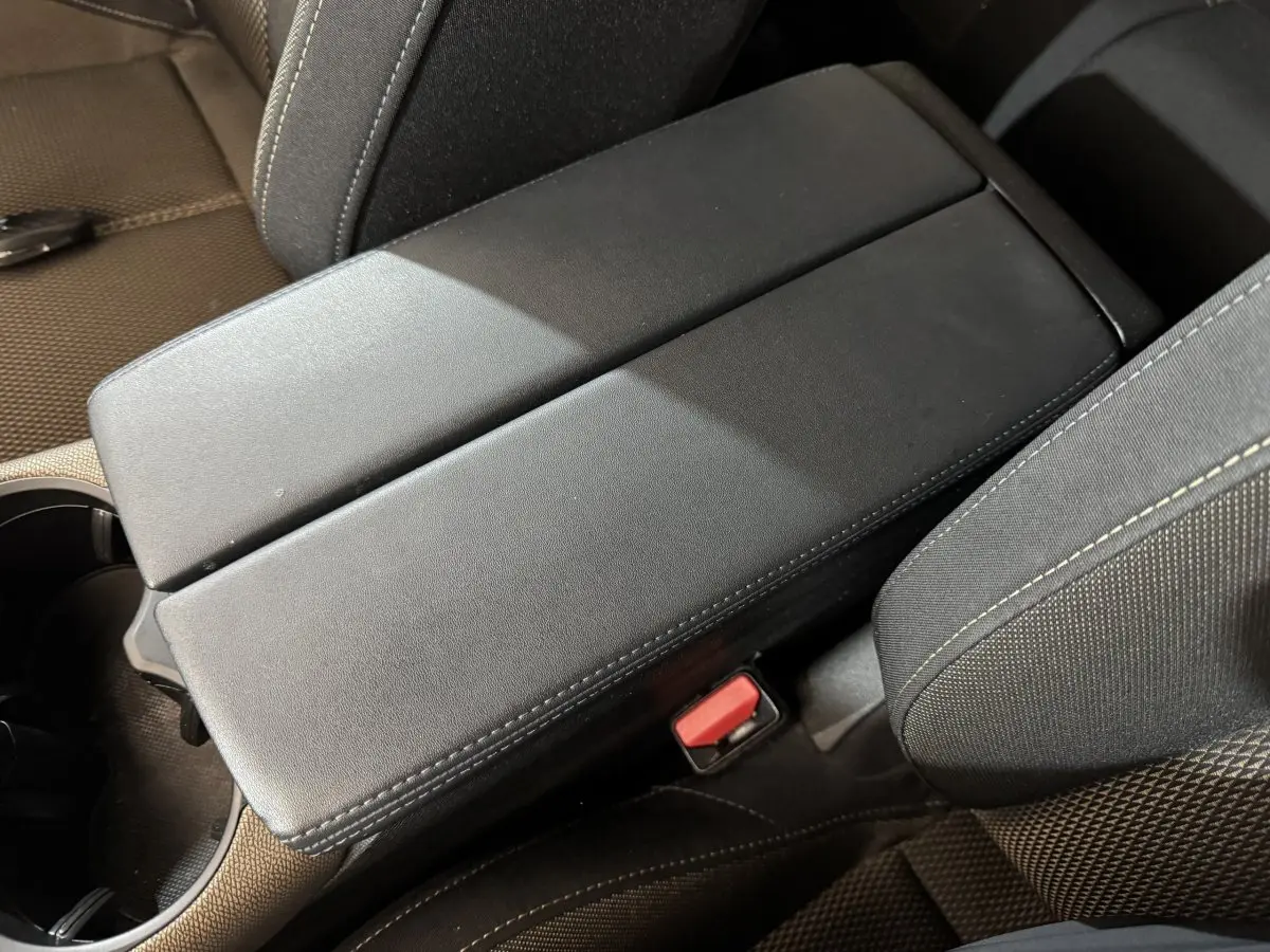 Gros plan sur l'accoudoir central noir et les sièges en tissu gris foncé du DS7 Crossback PureTech 130 Business.