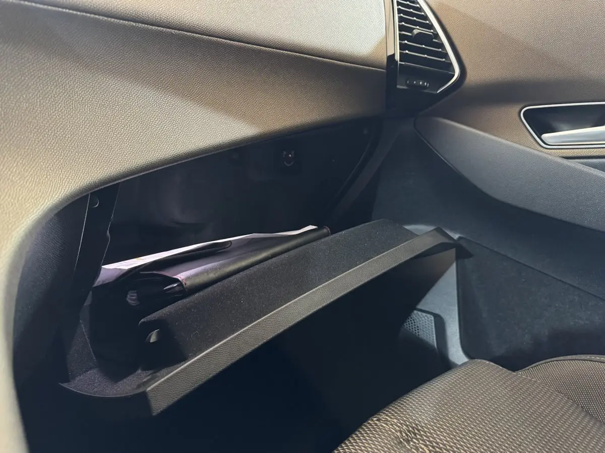 Vue intérieure côté passager du coffre à gants ouvert du DS7 Crossback gris foncé, montrant des documents à l'intérieur.