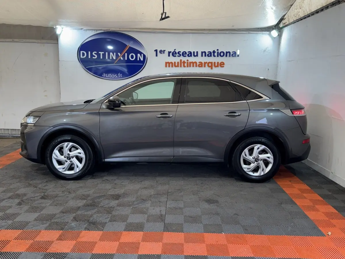 Vue latérale droite d'un DS7 Crossback gris foncé garé en intérieur avec vitres teintées et jantes argentées.