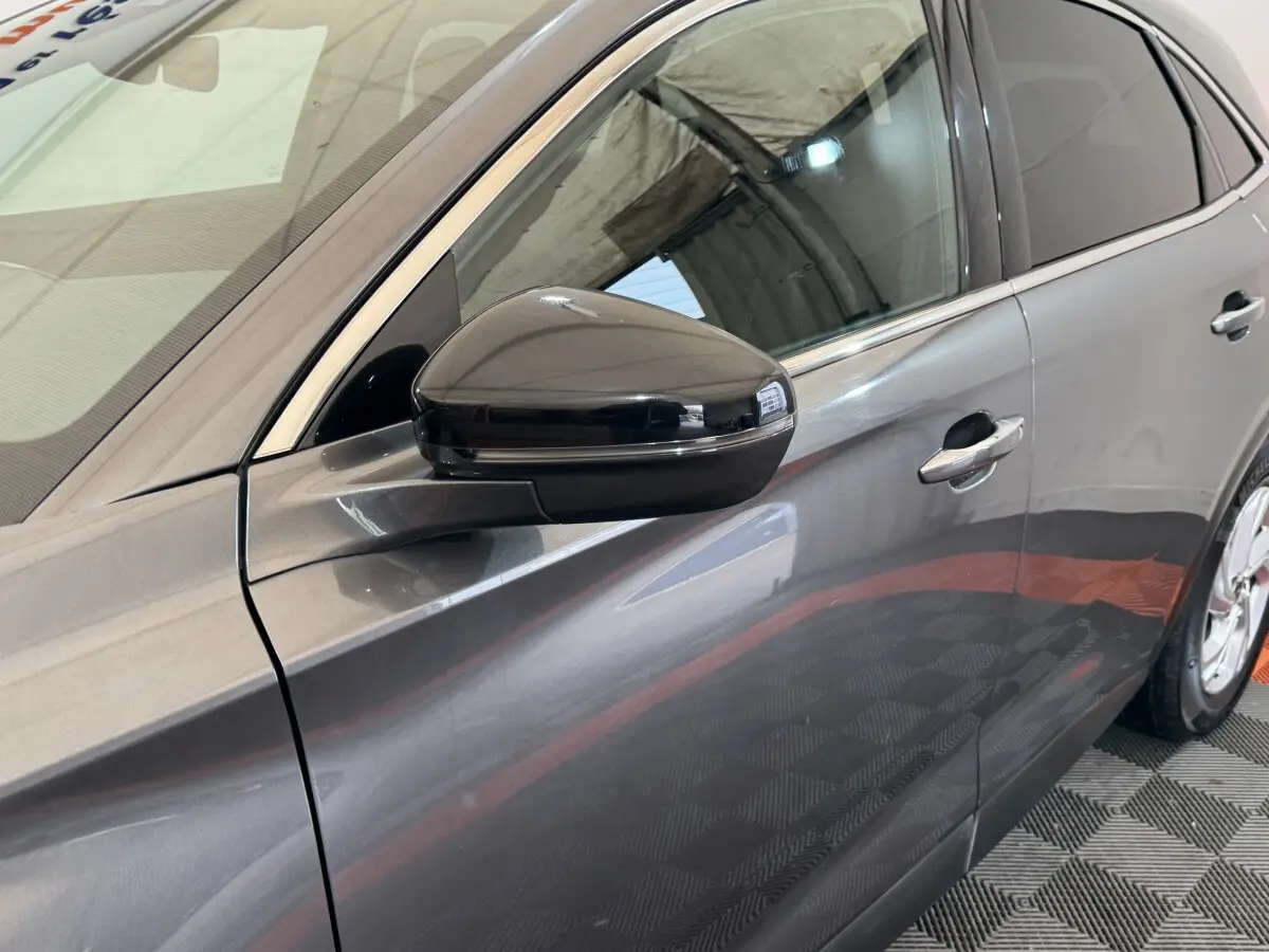 Vue latérale gauche rapprochée du DS7 Crossback gris foncé, mettant en valeur le rétroviseur noir brillant et les poignées de porte chromées.