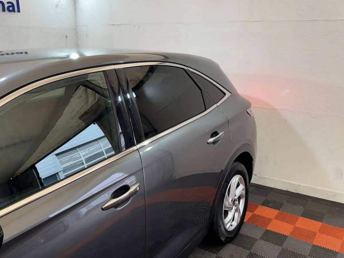 Vue côté droit arrière du DS7 Crossback gris foncé, mettant en valeur les vitres teintées et les jantes argentées.