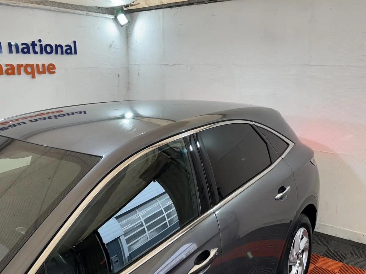 Vue 3/4 arrière côté gauche d'un DS7 Crossback gris foncé avec vitres teintées dans un garage.