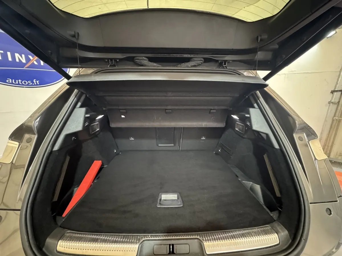 Vue arrière du coffre ouvert d'un DS7 Crossback gris foncé, montrant un espace de chargement spacieux et bien fini.