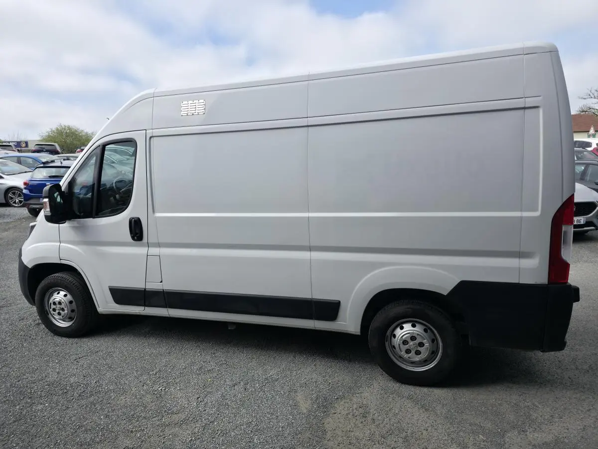 Vue de profil côté gauche d’un utilitaire Peugeot Boxer blanc avec porte latérale coulissante et baguettes de protection noires.