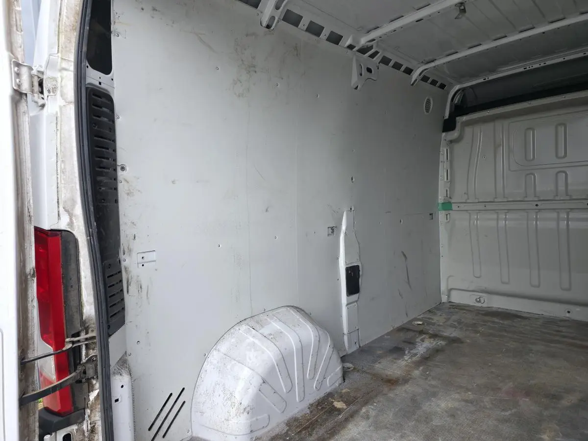 Vue intérieure de la cellule de chargement blanche du Peugeot Boxer Fourgon, montrant la cloison et le plancher usé.