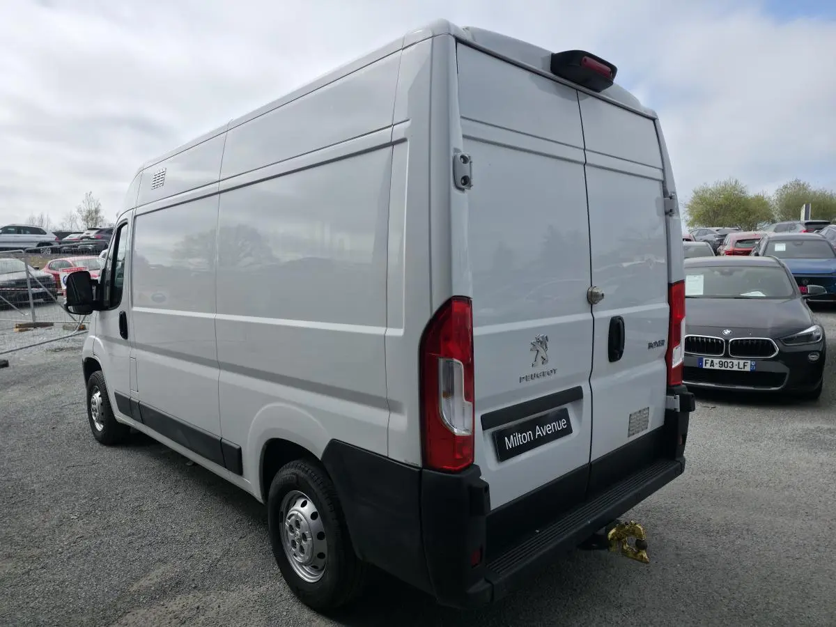 Vue 3/4 arrière droite du Peugeot Boxer Fourgon blanc avec crochet d'attelage et portes arrière battantes fermées.