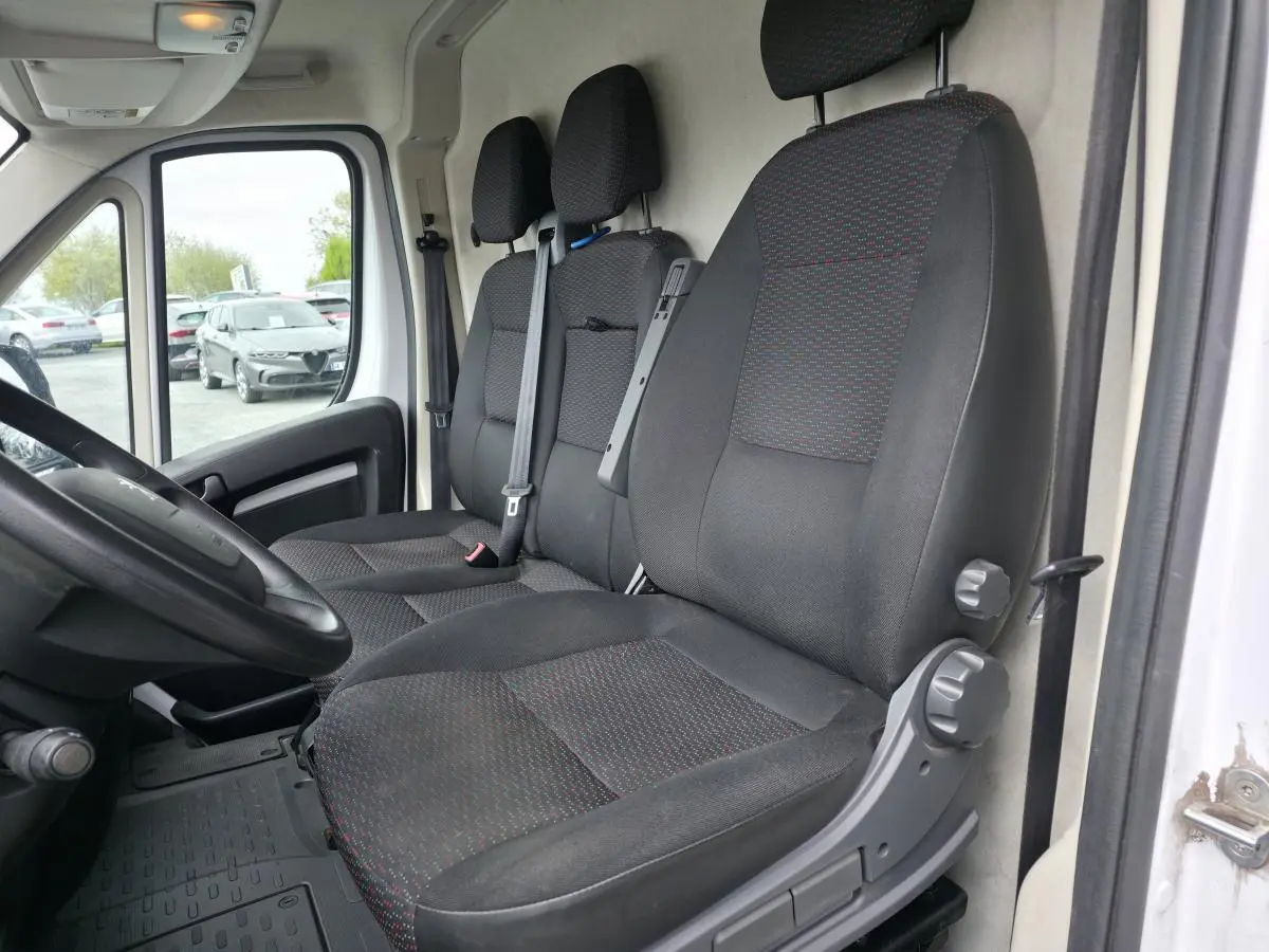 Vue intérieure côté conducteur du Peugeot Boxer Fourgon blanc 2022, montrant les sièges tissu Darko et le volant.