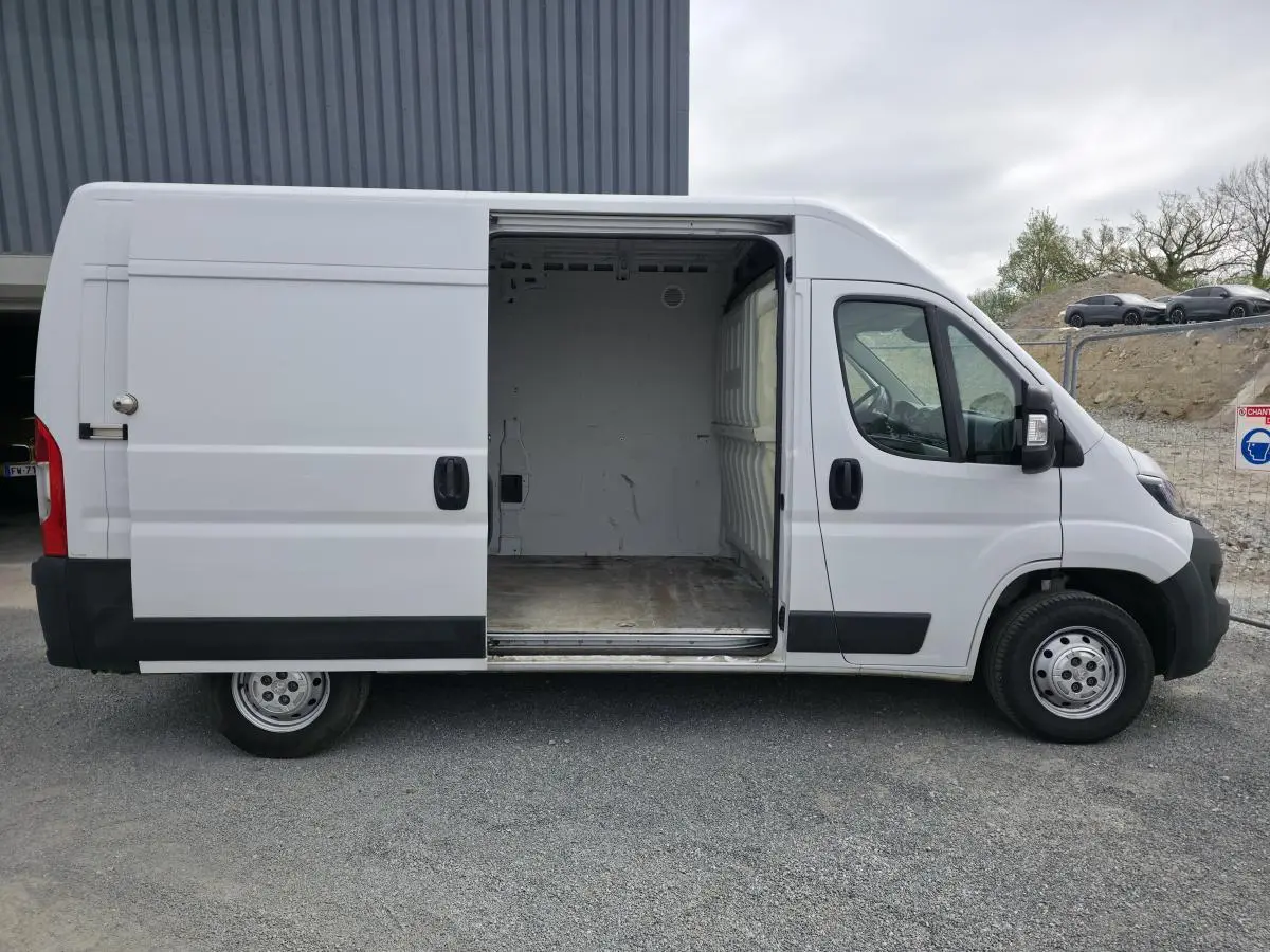 Vue latérale droite d'un Peugeot Boxer Fourgon blanc avec porte coulissante ouverte montrant la cellule de chargement vide.