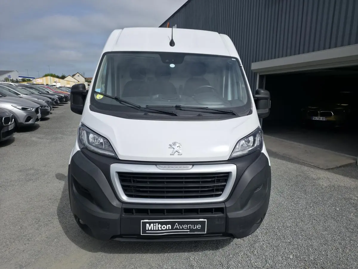 Vue avant d'un Peugeot Boxer Fourgon blanc avec pare-chocs noirs et calandre imposante sur parking.