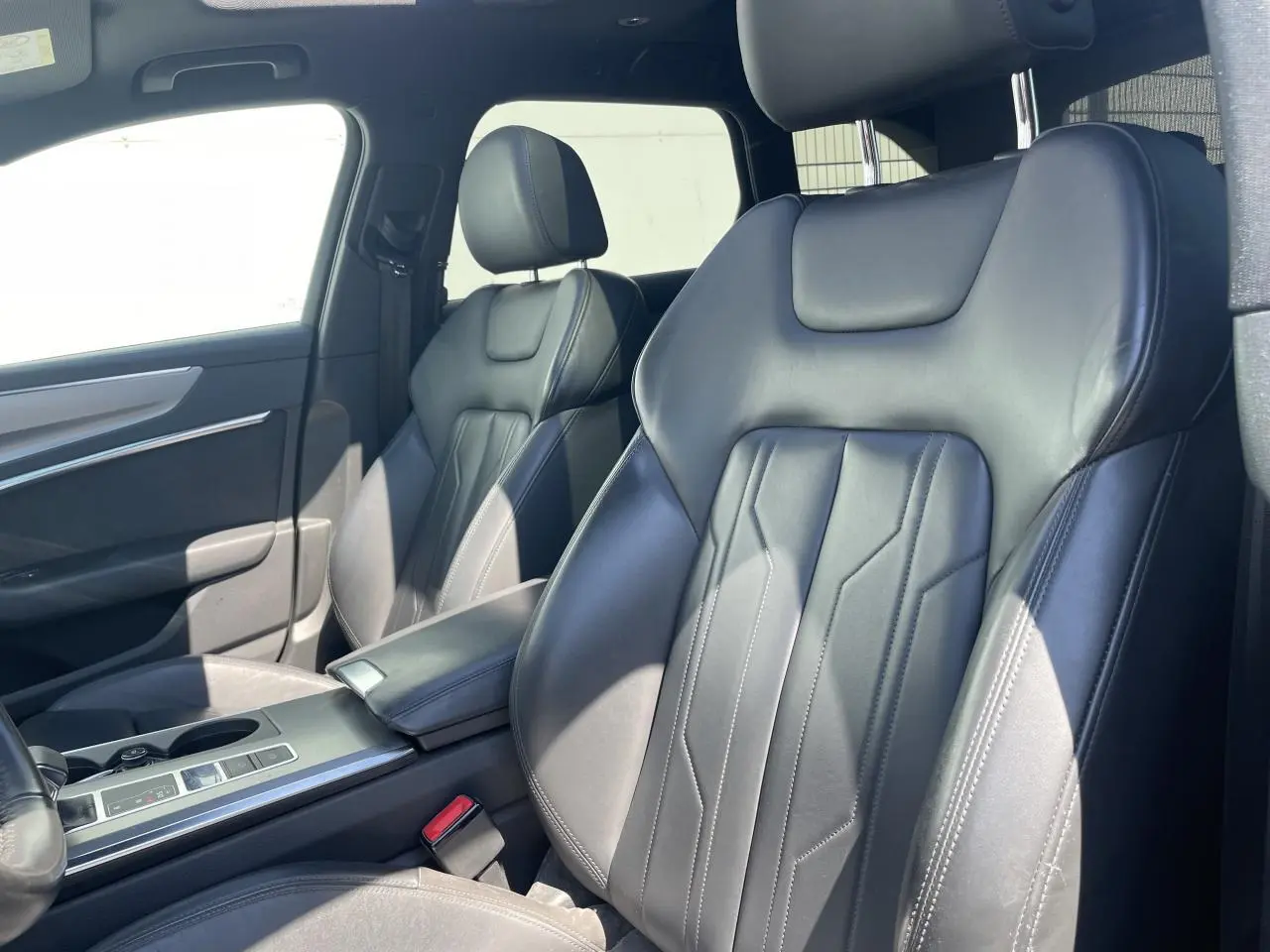 Vue intérieure côté avant droit montrant les sièges en cuir noir et l'accoudoir central de l'Audi A6 V Avant 2019.