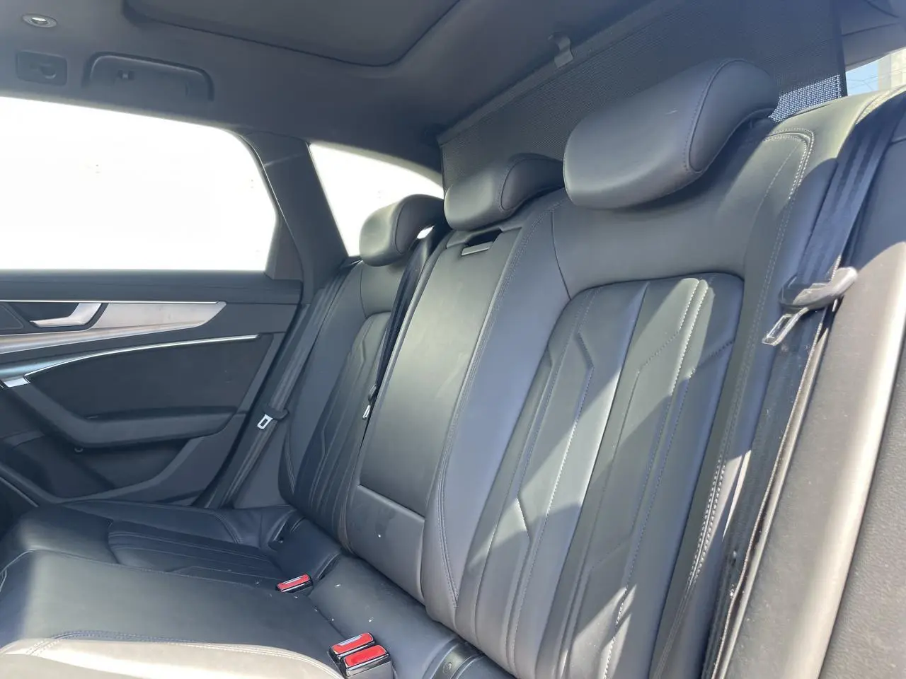 Vue intérieure de la banquette arrière en cuir noir de l'Audi A6 V Avant 2019, avec appuie-têtes et ceintures visibles.