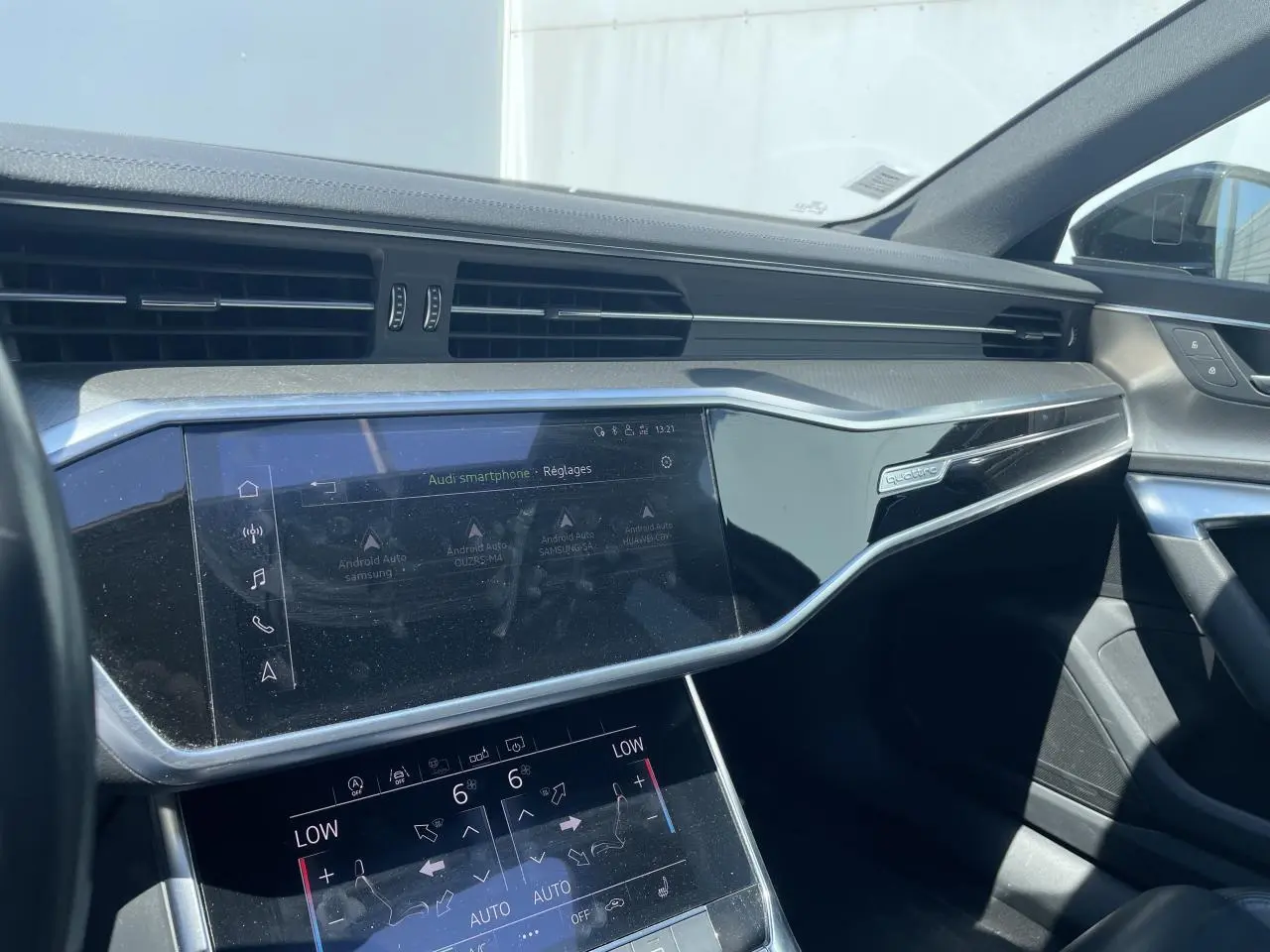Vue intérieure côté passager de l'Audi A6 2019 noire, mettant en valeur le tableau de bord et l'écran tactile central.