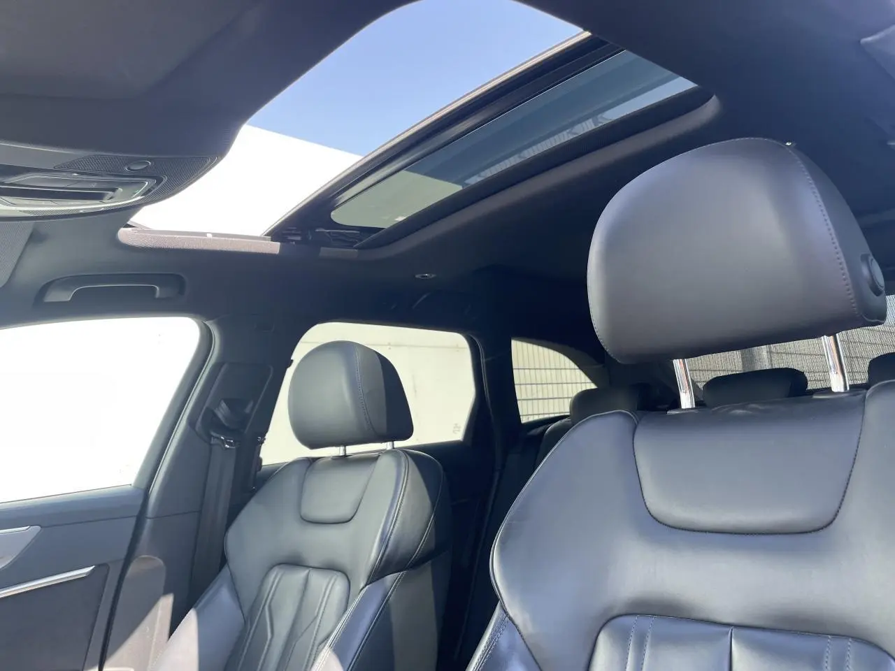 Intérieur noir cuir de l'Audi A6 2019, vue rapprochée des sièges avant avec toit panoramique ouvert.