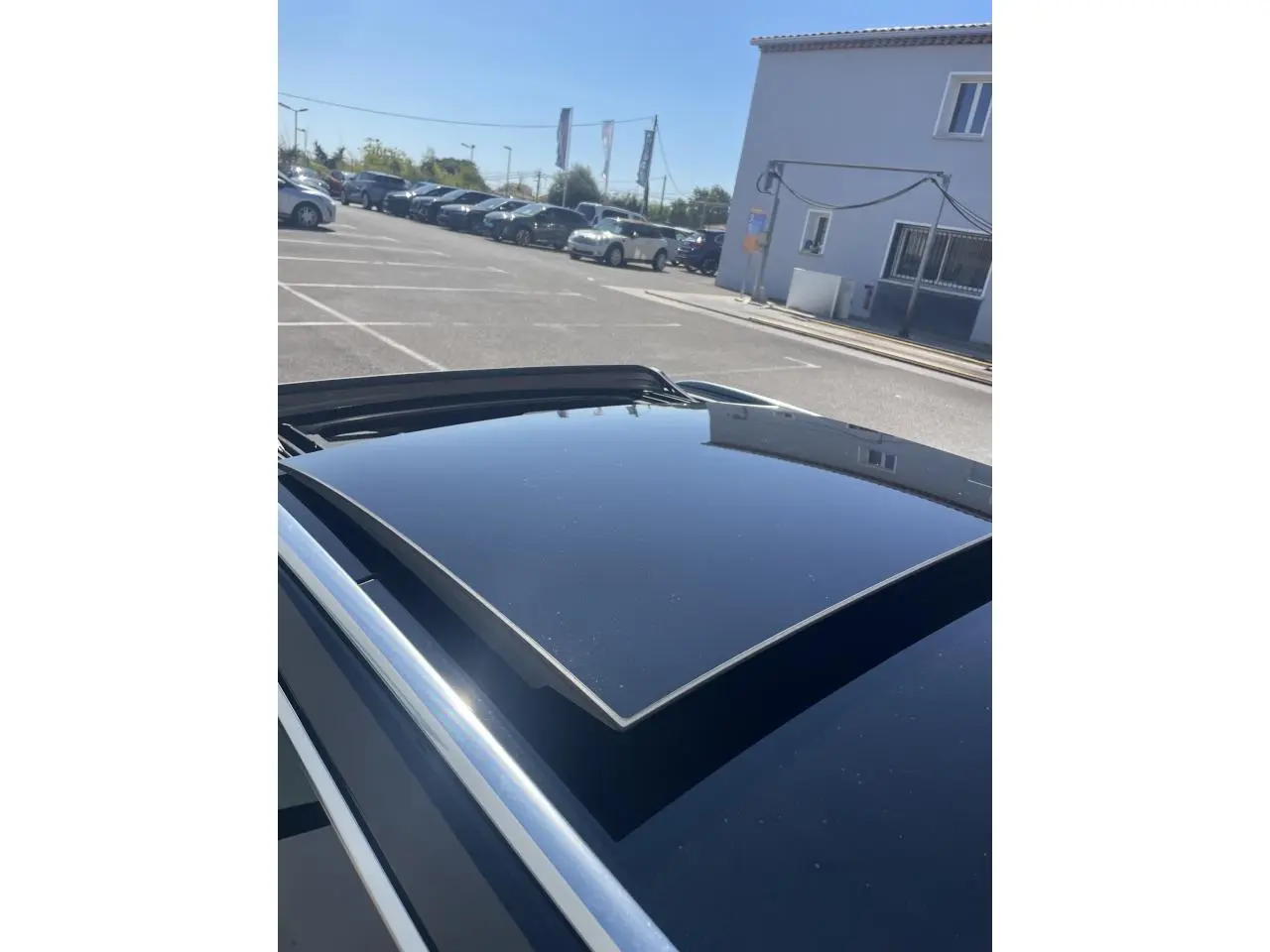 Toit panoramique en verre ouvert sur Audi A6 noir métal, vue en plongée depuis l'arrière droit du véhicule.