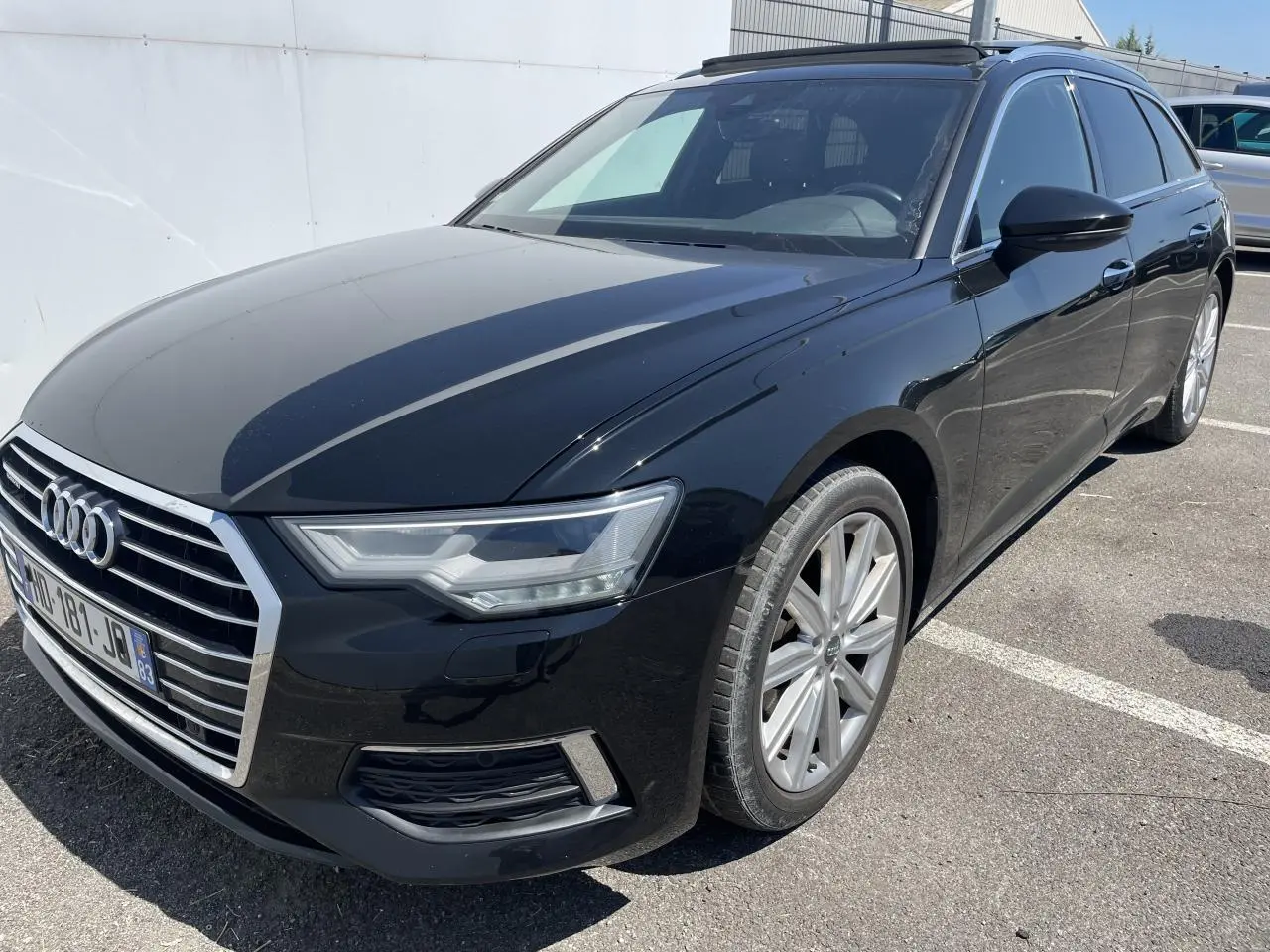 Audi A6 noir métal vue 3/4 avant droit, avec calandre chromée et jantes aluminium 10 branches visibles.