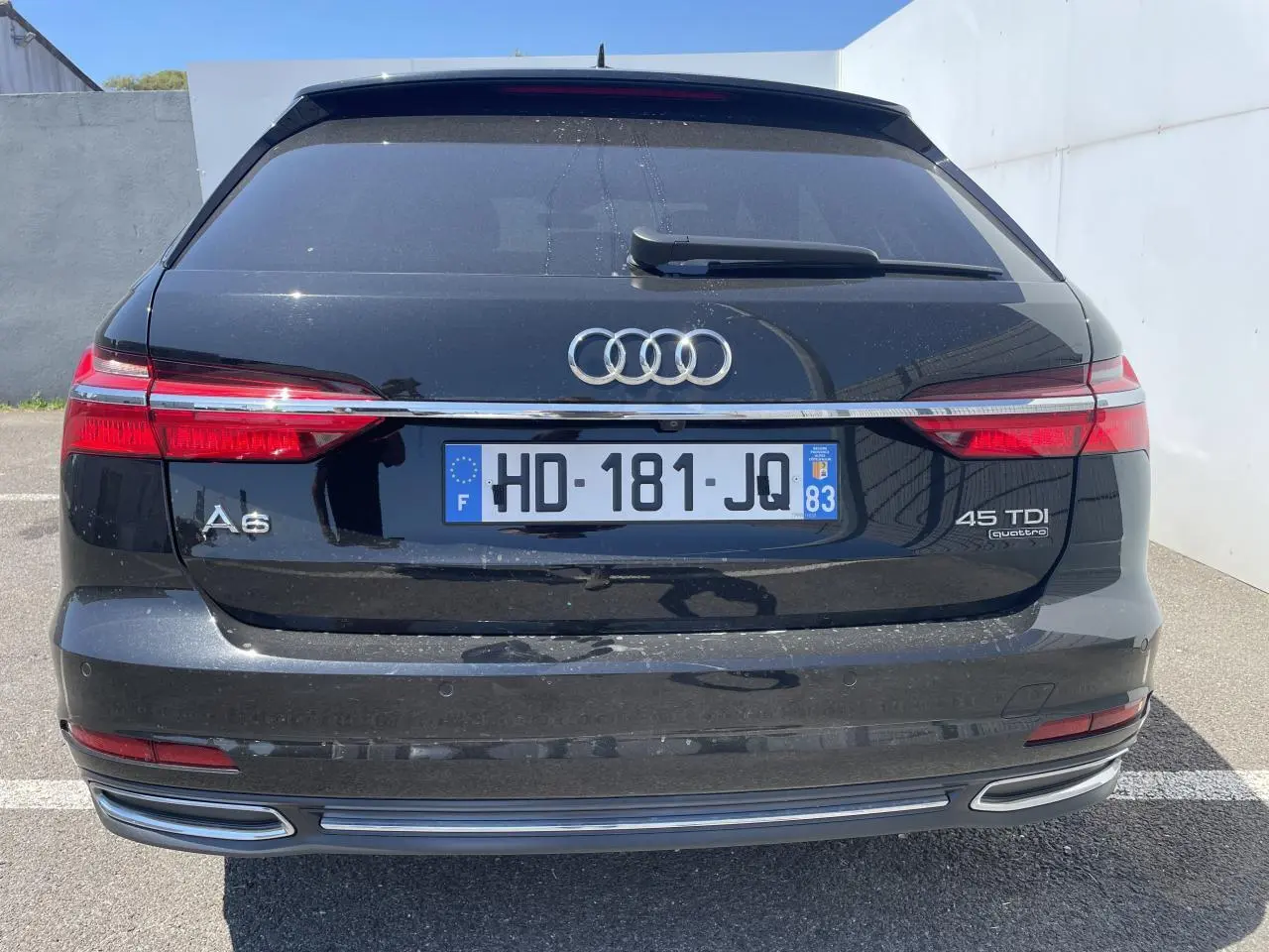 Vue arrière d'une Audi A6 noire métal 45 TDI Quattro avec feux LED et double sortie d'échappement intégrée.