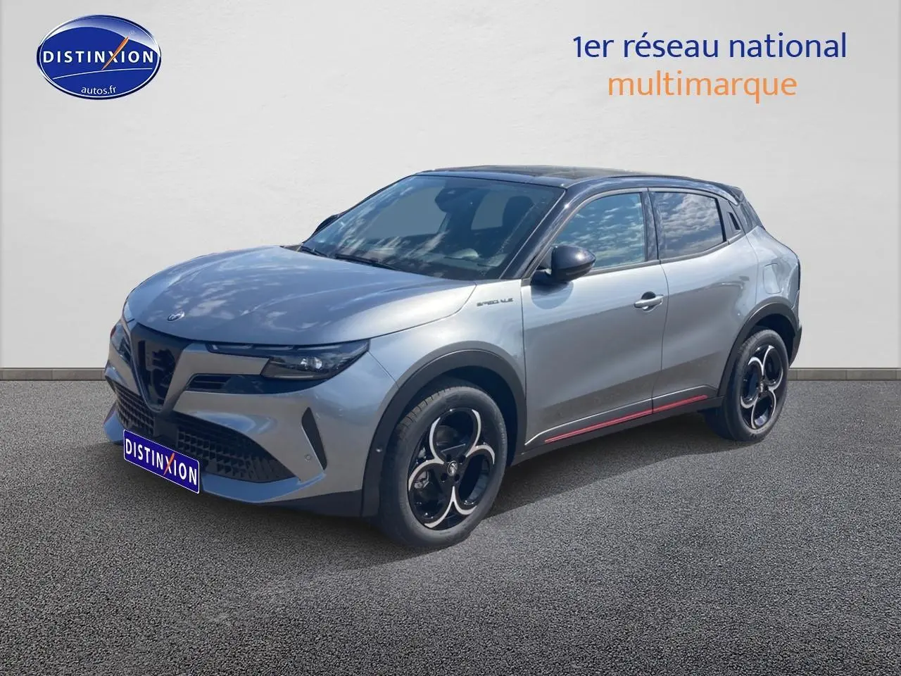 Vue 3/4 avant droite d'une Alfa Romeo Junior 1.2 hybride gris clair avec jantes noires et toit noir.