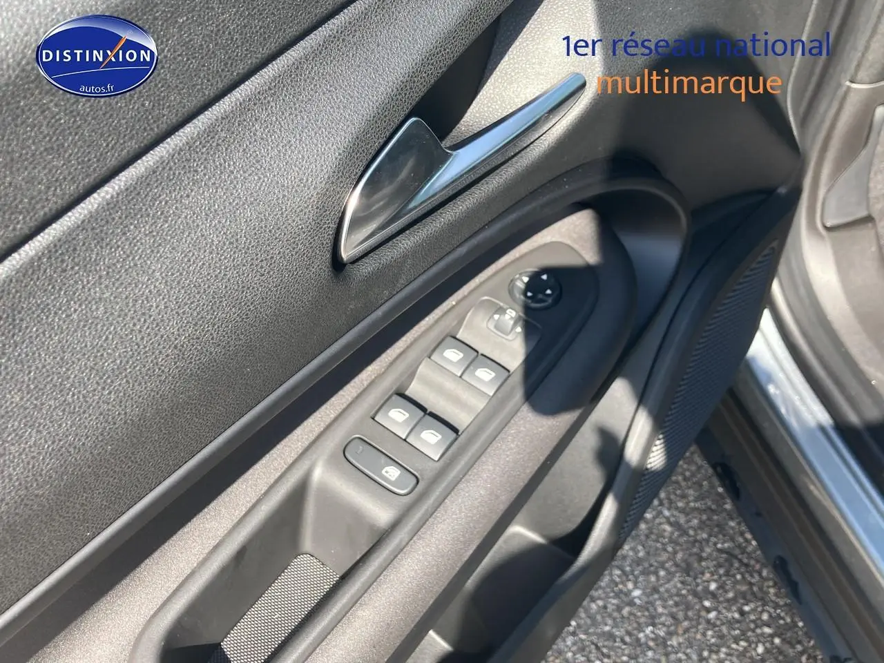 Vue rapprochée de la porte avant gauche grise de l'Alfa Romeo Junior 1.2 hybride, avec commandes électriques et haut-parleur intégré.
