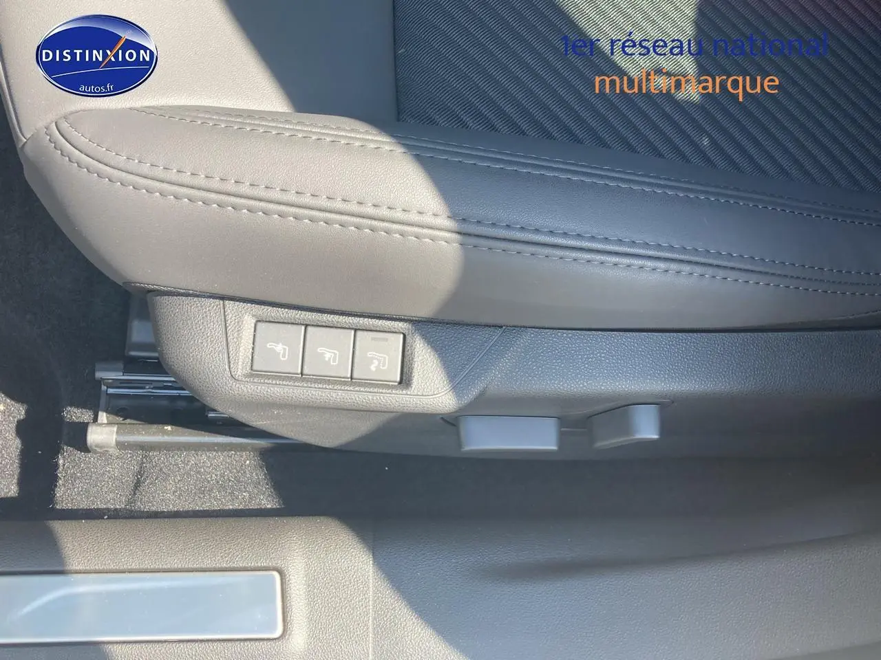 Gros plan sur le siège conducteur gris clair de l'Alfa Romeo Junior 1.2 hybride, avec commandes électriques visibles.