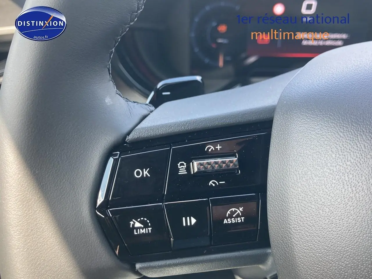 Gros plan sur les commandes au volant de l'Alfa Romeo Junior 1.2 hybride, finition gris t/noir, avec boutons de régulateur et assistance.