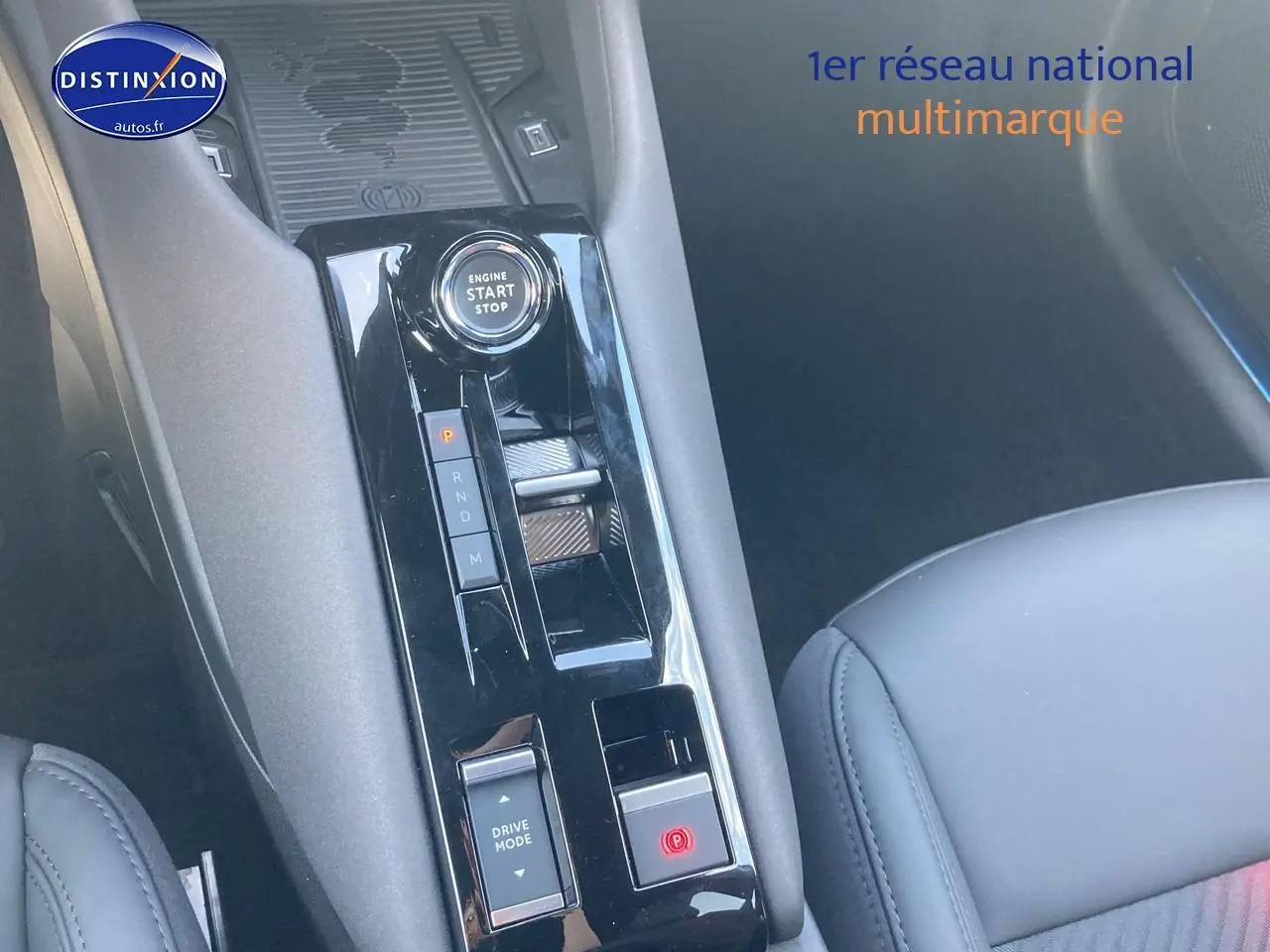 Gros plan sur la console centrale noire brillante de l'Alfa Romeo Junior 1.2 hybride, avec bouton start/stop et levier de boîte auto.